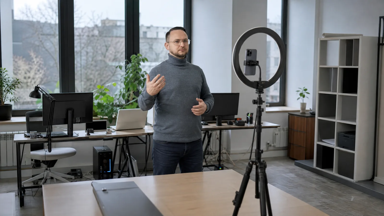 Дмитрий Рогачев снимает вертикальное видео на телефон с кольцевой лампой в офисе